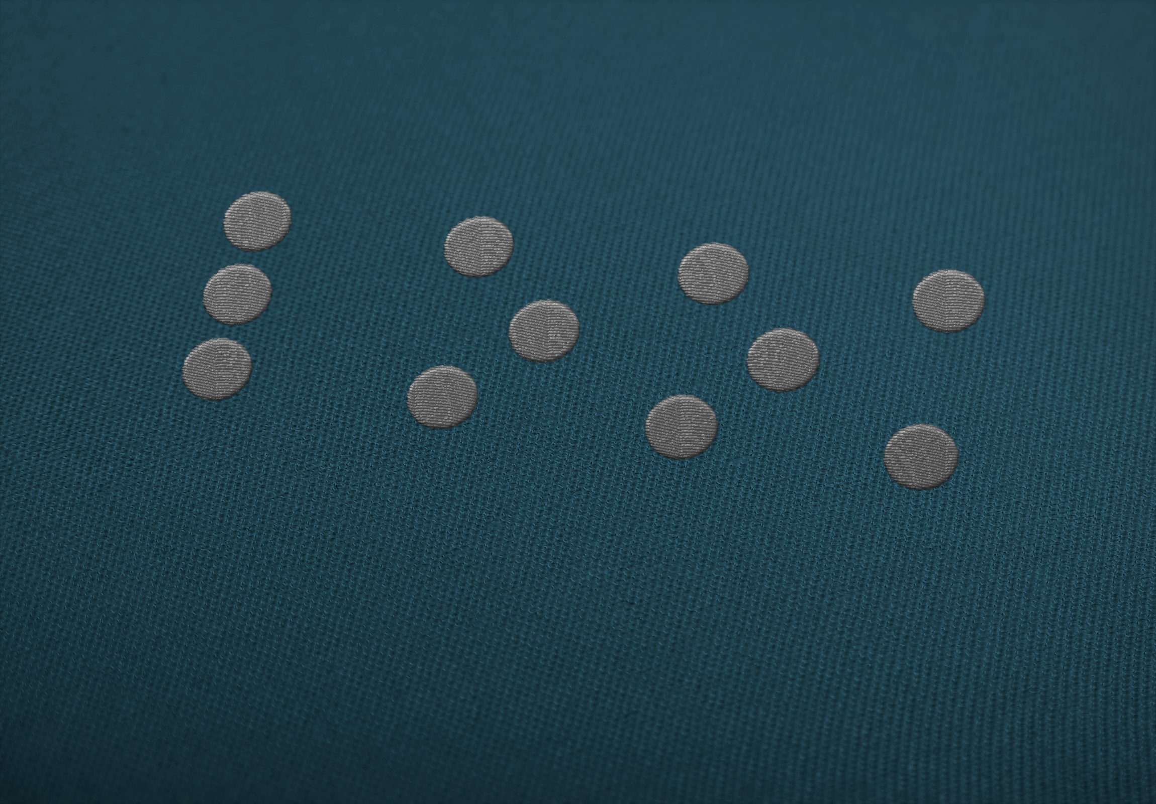 Braille mark embroidered on teal fabric