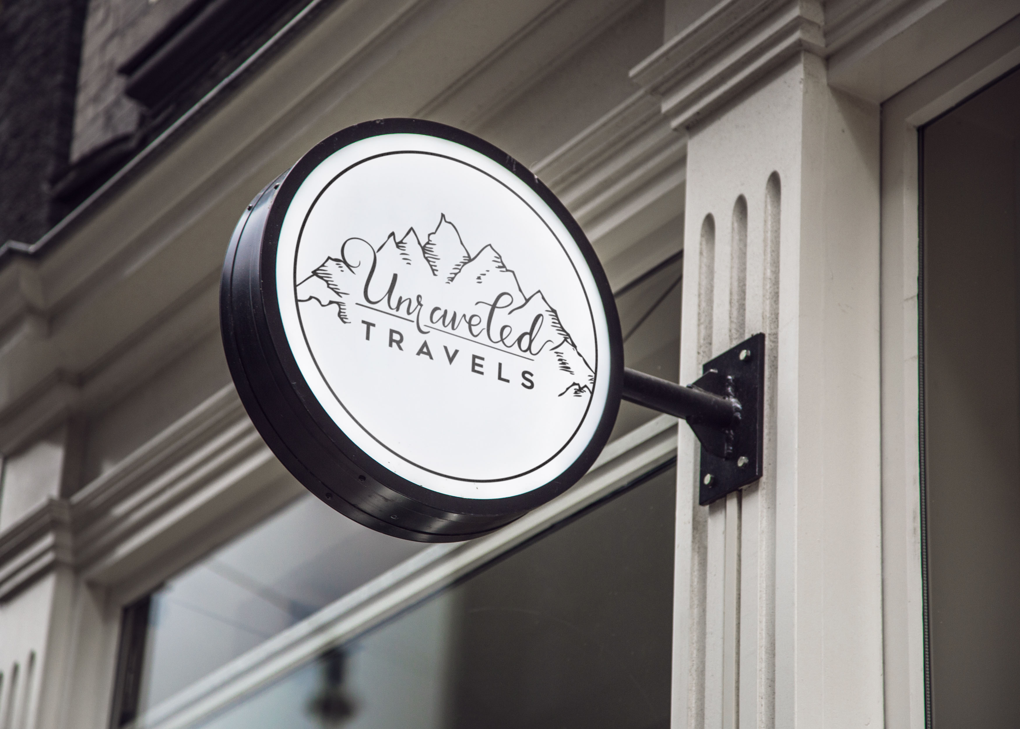 Unraveled Travels hanging storefront sign